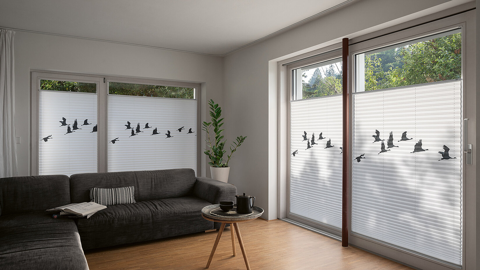 Living room with white pleated blinds featuring a printed silhouette of flying birds.