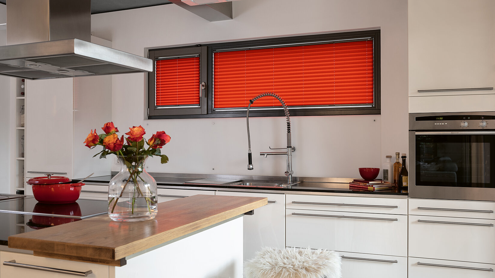 Modern kitchen with narrow windows covered by bold red pleated blinds.