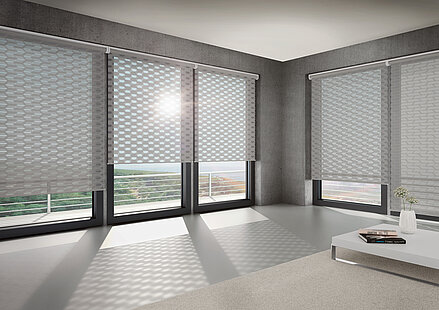 Wohnzimmer mit großen Fenstern und geometrisch gemusterten Doppelrollos vom Typ „Logan“ von MHZ, die ein gleichmäßiges Lichtmuster auf dem Boden erzeugen.