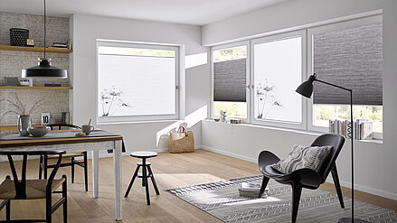 Wohn- und Essbereich mit weißen und grauen Wabenplissees, teilweise mit floralem Druckmotiv, als Sicht- und Wärmeschutz