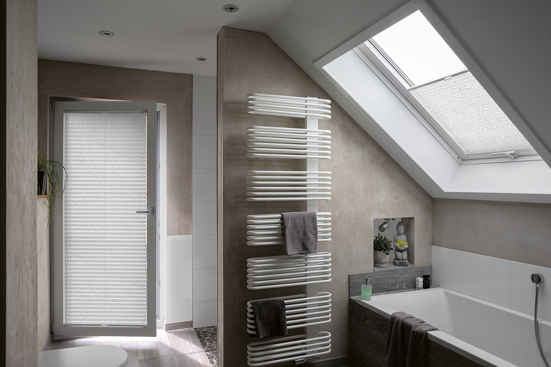 Modernes Badezimmer mit weißen Plissees an Tür und Dachfenster als Sichtschutz.