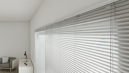 Horizontale Innenjalousien aus Aluminium vor großen Fenstern in einem modernen, hell eingerichteten Raum.