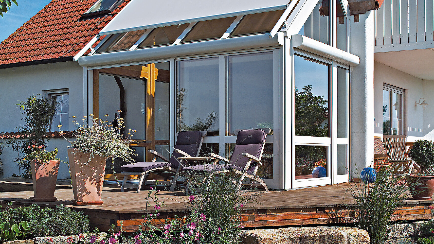 White exterior awning on sloped glass roof of a conservatory at a detached house.