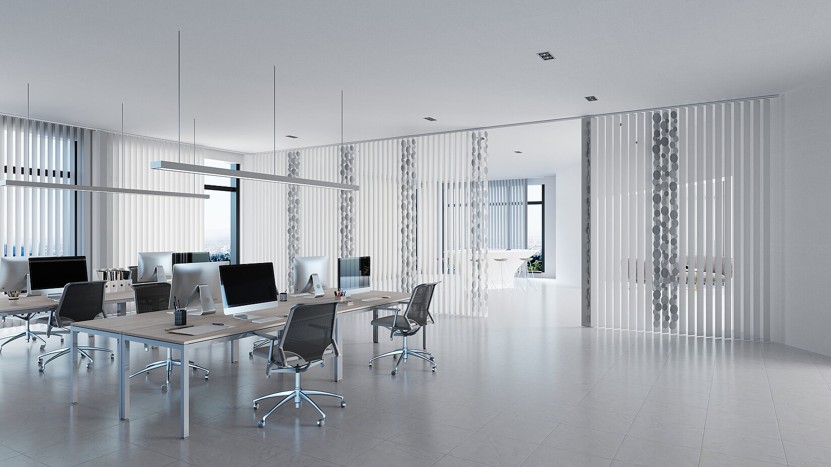 Modern open-plan office with white vertical blinds on the windows and several desks with monitors