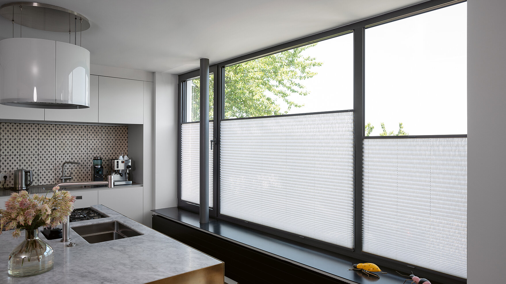 Weiße Plissees im unteren Fensterbereich in moderner Küche mit großen Fensterflächen.