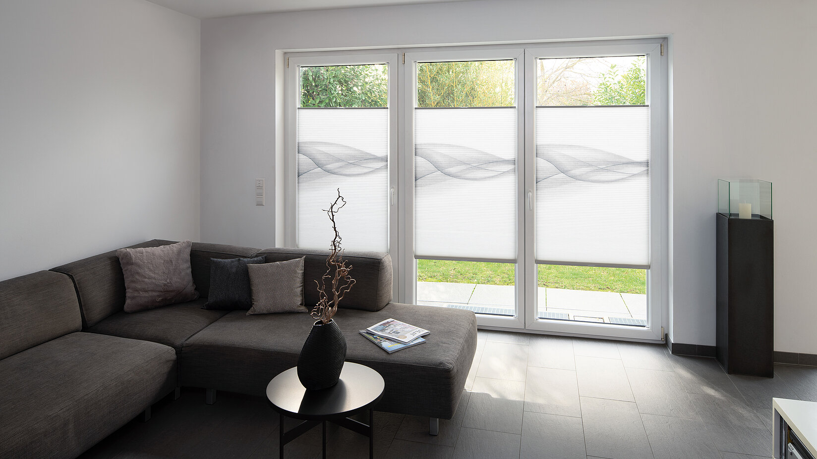 Floor-to-ceiling windows with grey patterned honeycomb blinds in a modern living room.